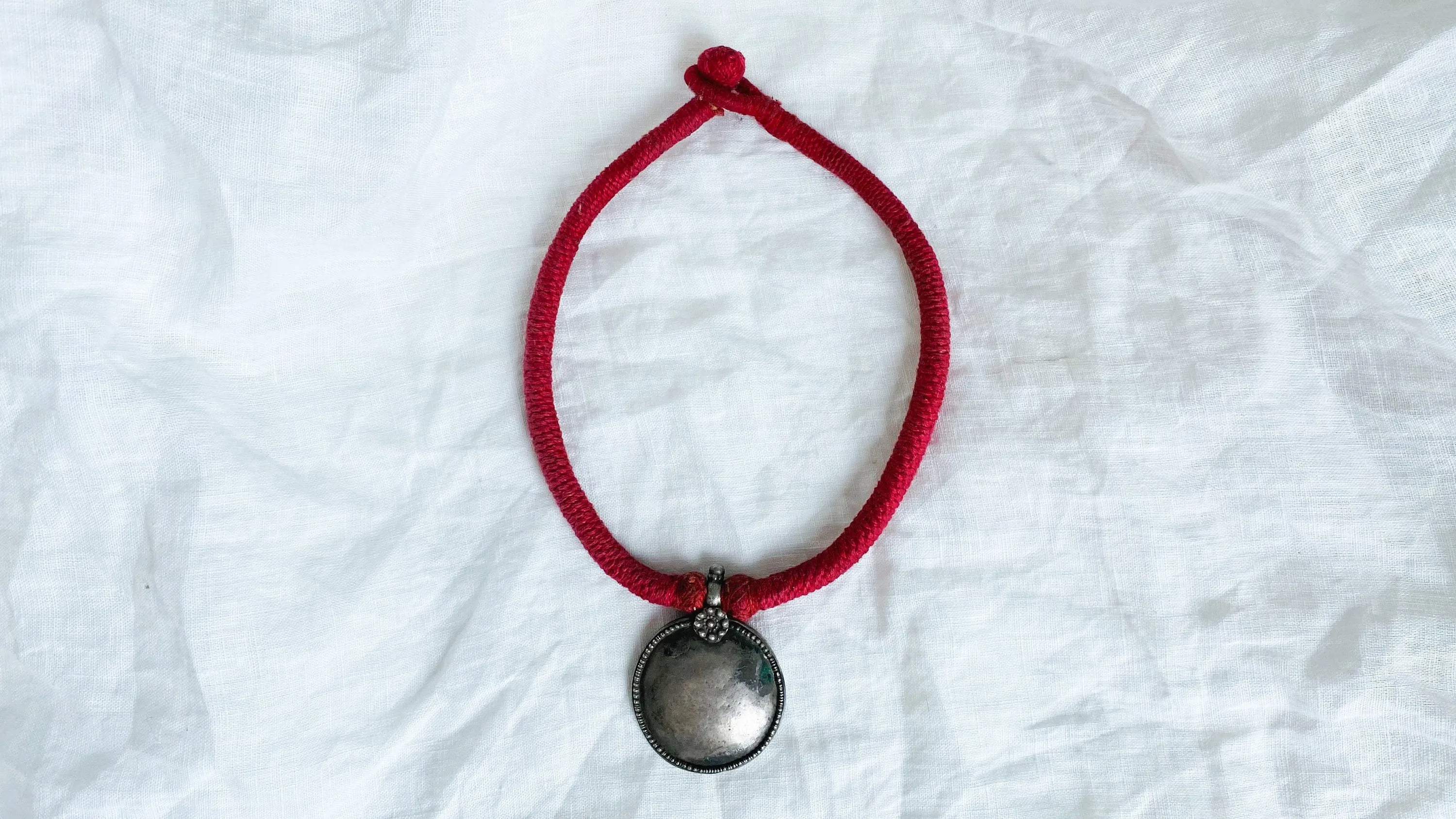 Antique Indian Silver Pendant on a Wrapped Red Cord.